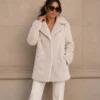 KennedyCoat_Pearl Woman wearing the Kennedy plush faux fur coat in pearl over white trousers, front view