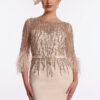 Close-up of the sequin and beaded sheer top and feather cuffs on a champagne dress Close-up of the sequin and beaded sheer top and feather cuffs on a champagne dress